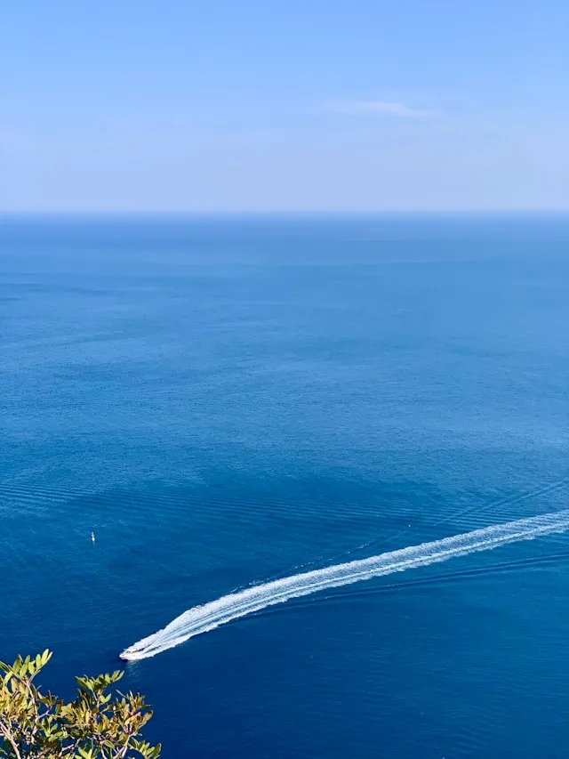 A boat carving a wake across deep blue sea
