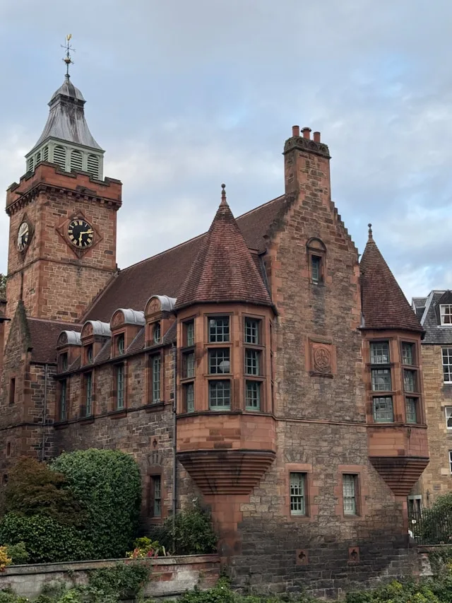 Sandstone clock tower under a clouded sky